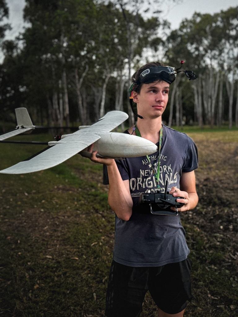 Samuel holding a custom-built fixed-wing aircraft outdoors